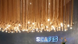 A reception area with a modern design, featuring a wooden reception desk and a unique hanging light fixture above. - SCAPES Hotel (Genting Highlands)