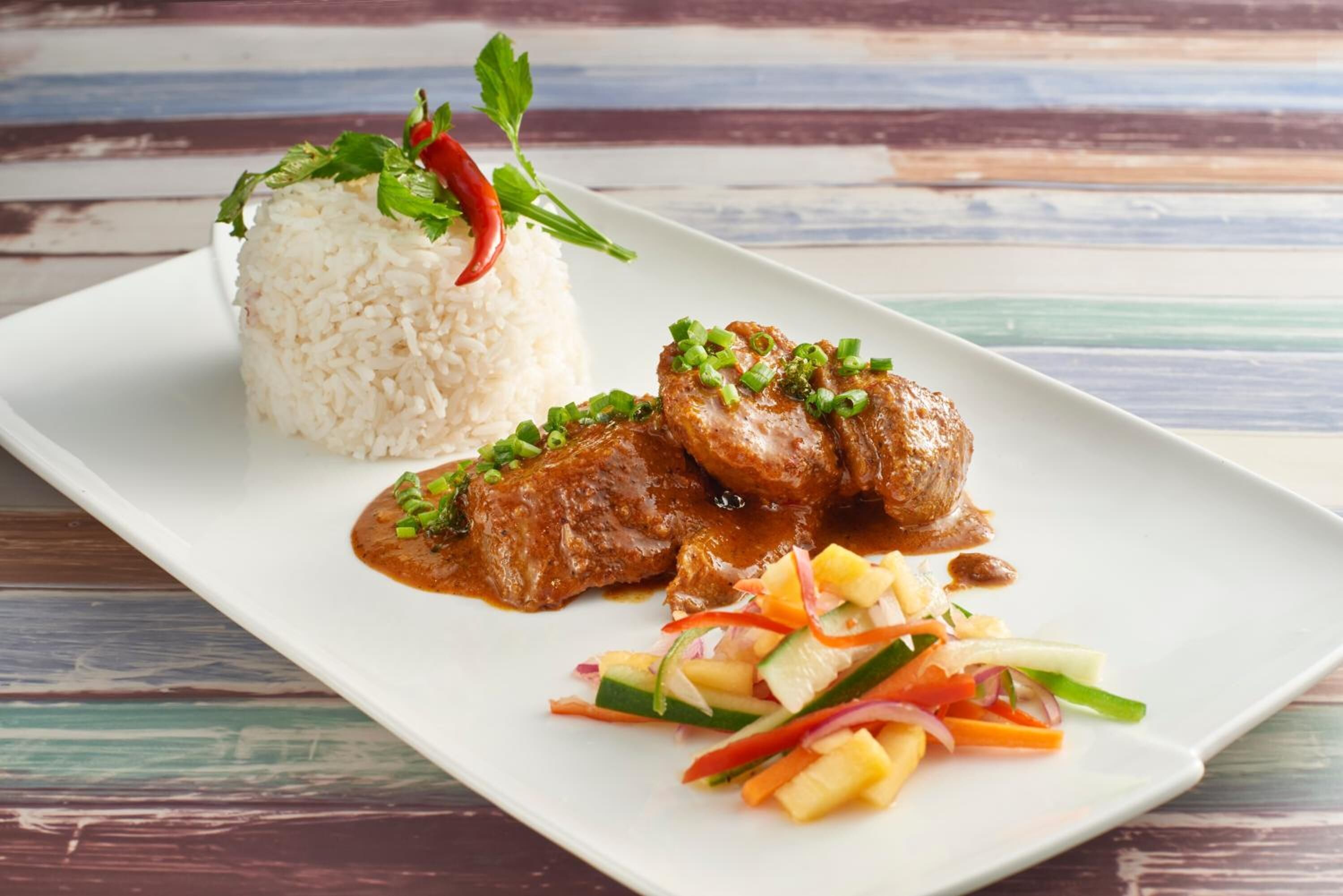 A plate with white rice, grilled meat, and a vegetable salad.