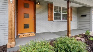 A house with a wooden door, a window with shutters, and a porch with a welcome mat. - the ORANGE DOOR just steps from art, trails & dining (Bentonville)