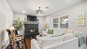 A living room with a fireplace, a sofa, a TV, and a ceiling fan. - the ORANGE DOOR just steps from art, trails & dining (Bentonville)