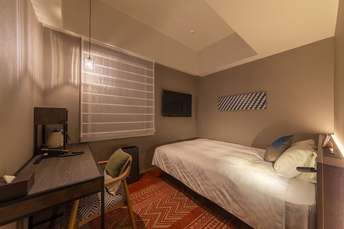 Une chambre d’hôtel équipée d’un lit, d’un bureau, d’une chaise et d’un téléviseur.