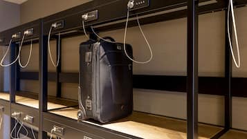 A row of black lockers with a suitcase hanging on one of them.