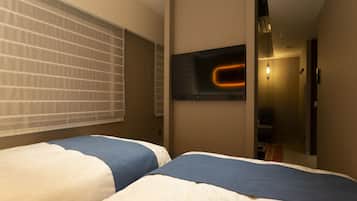 Une chambre d’hôtel avec deux lits, un grand miroir et un couloir menant à un espace détente.
