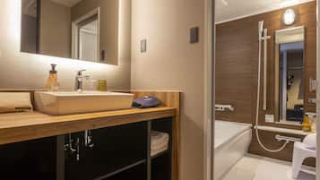 Un baño moderno con un lavamanos grande, espejo y ducha.