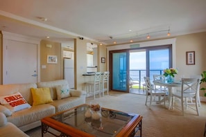 A living room with a sofa, coffee table, and dining area with chairs. - Perfect Sunsets - Unobstructed views of the ocean (La Jolla)