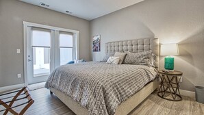 A bedroom with a large bed, a side table with a lamp, a door, and a window. - Wonderful Three Bedroom Townhome in Old Town North (Fort Collins)