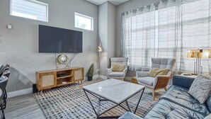 A modern living room with a flat-screen TV, two armchairs, a sofa, and a coffee table. - Wonderful Three Bedroom Townhome in Old Town North (Fort Collins)