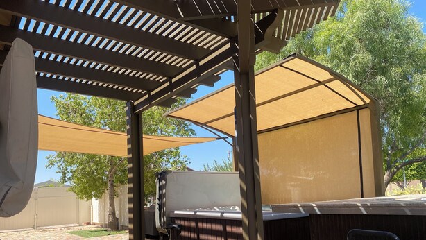 Un patio al aire libre con una parrilla, asientos y una estructura de pérgola.