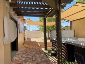 A covered patio area with a brick floor, outdoor seating, and a grill. - 3-Bed 2 Bath Cozy Foothills Vacation Home (Yuma)