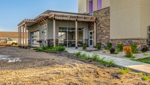 A building with a stone facade, a covered entrance with glass doors, and a parking area. - Clubhouse Fully Equipped Apartment (Mankato)