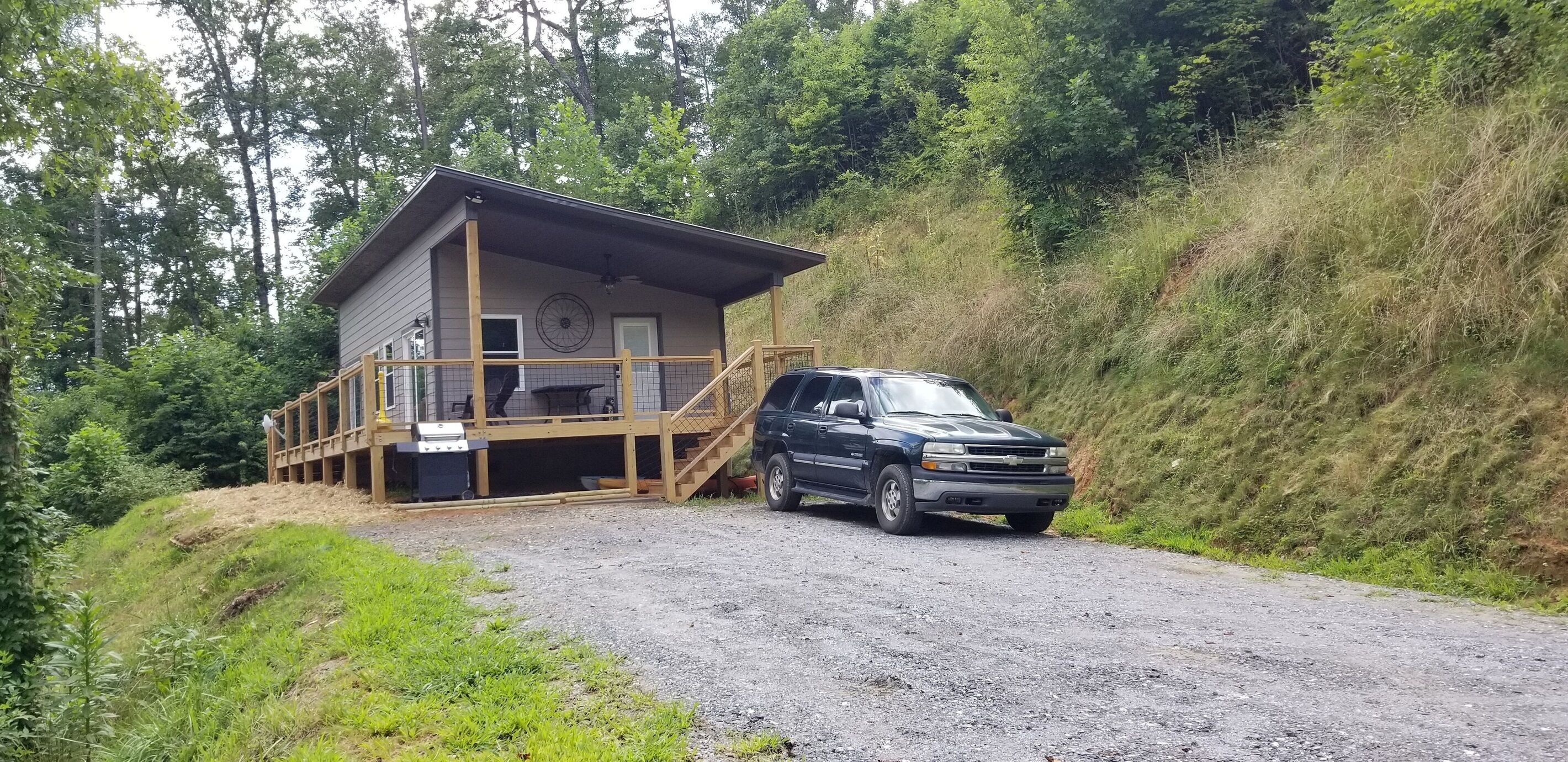 Una cabana amb un balcó de fusta i un vehicle estacionat al davant.