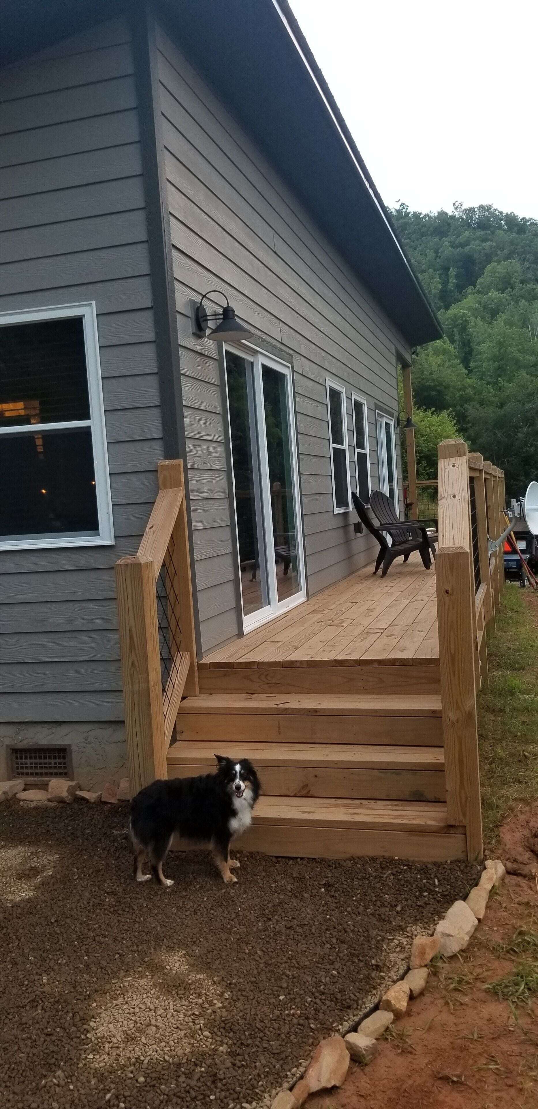 Une maison avec une terrasse en bois, un chien et une antenne parabolique.