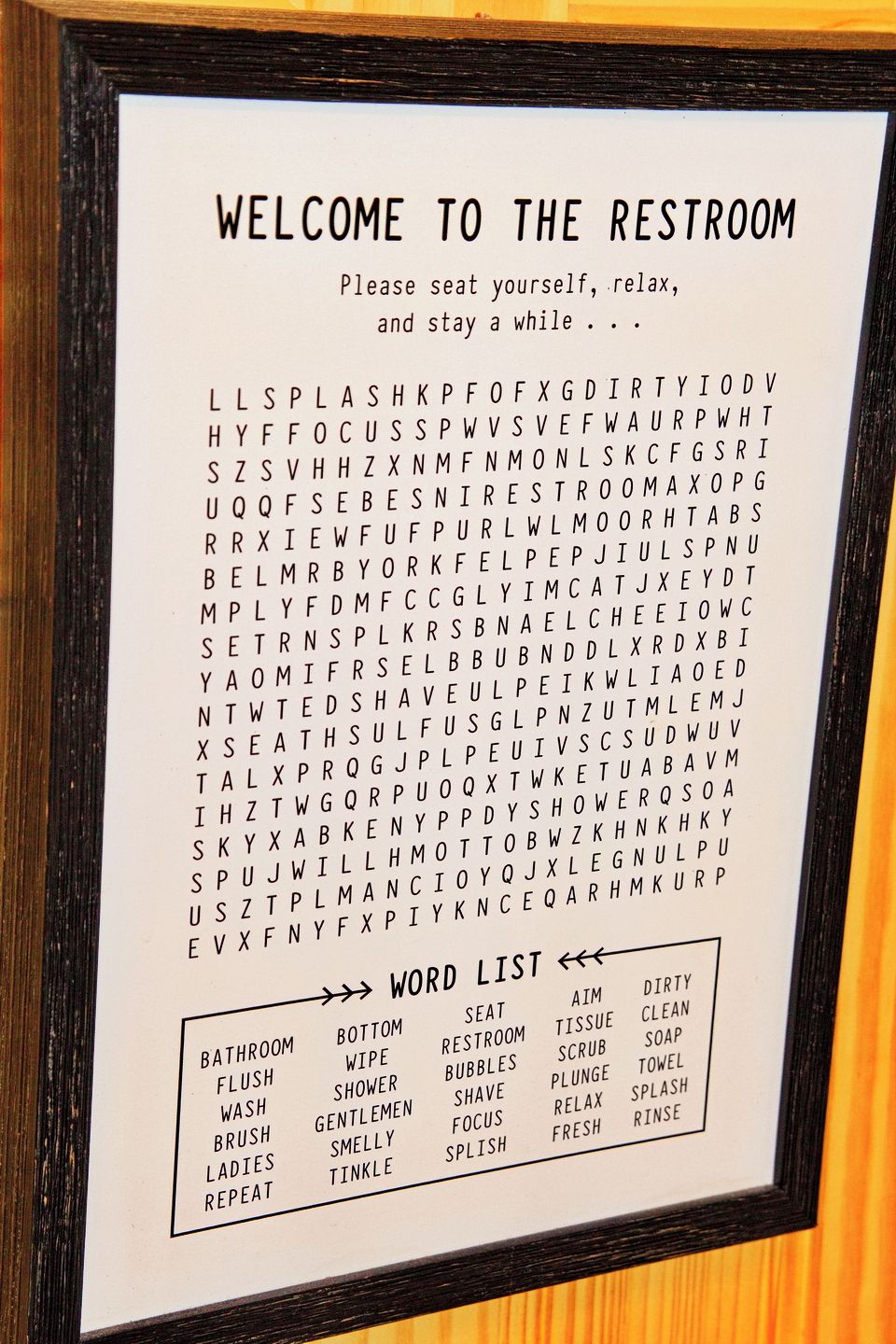A restroom sign with a word search puzzle and a list of words.