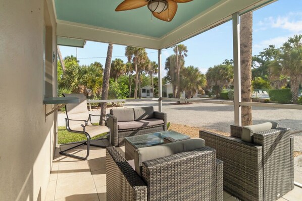 A covered outdoor seating area with wicker furniture and a ceiling fan.