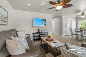 A living room with a sofa, coffee table, and a television mounted on the wall.