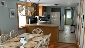 Una cocina amplia con armarios de madera, una isla central y un comedor con sillas de mimbre y una mesa de vidrio.