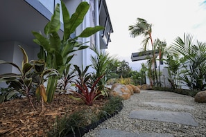 Stroll through the beautifully maintained garden, featuring a variety of plants along a gravel pathway leading to the building.