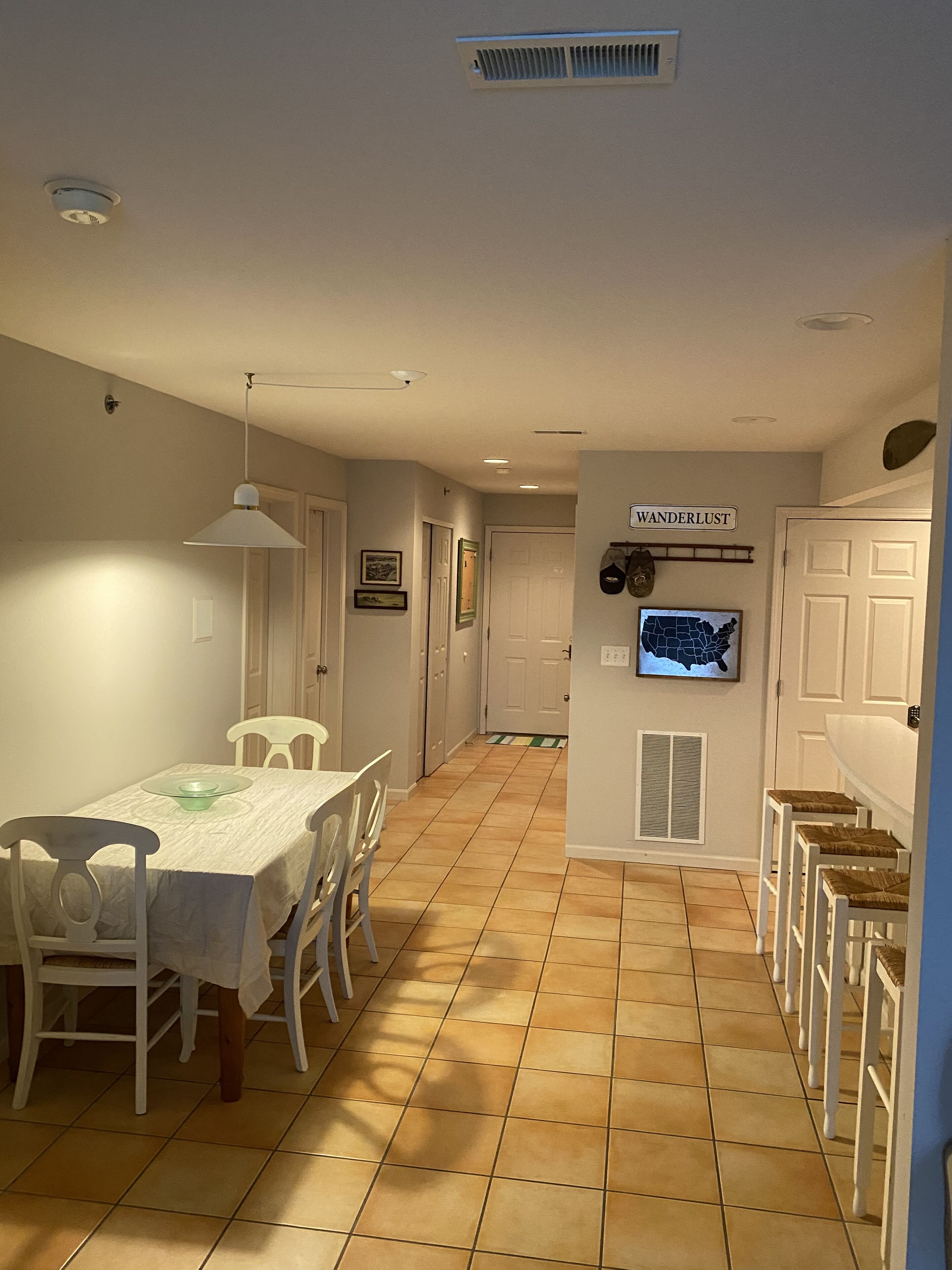 A dining area with a table and chairs, a wall-mounted map, and a sign reading "WANDERLUST".