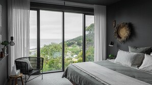 A bedroom with a large bed, a chair, and a view of the outdoors. - Months and Seasons - Coastal House - Stunning Views (Separation Creek)