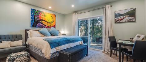 A bedroom with a bed, a bench, a desk, and chairs.