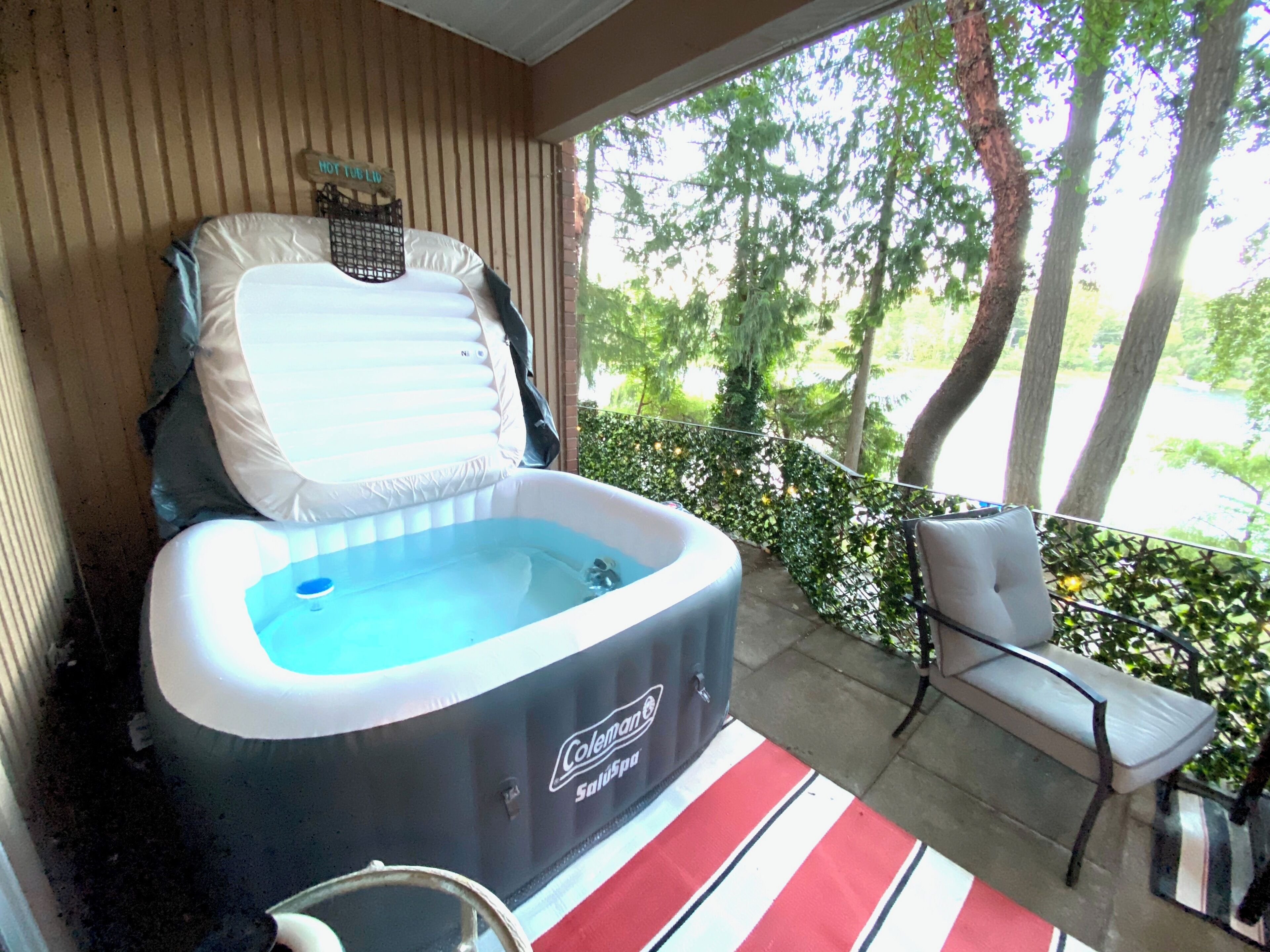 Ein Whirlpool auf einer überdachten Terrasse mit einem Stuhl und einem Tisch mit Streifenmuster.