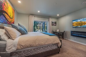 Ein Schlafzimmer mit einem Bett, einem Schreibtisch, einem Sessel und einem großen Fenster mit Vorhängen.