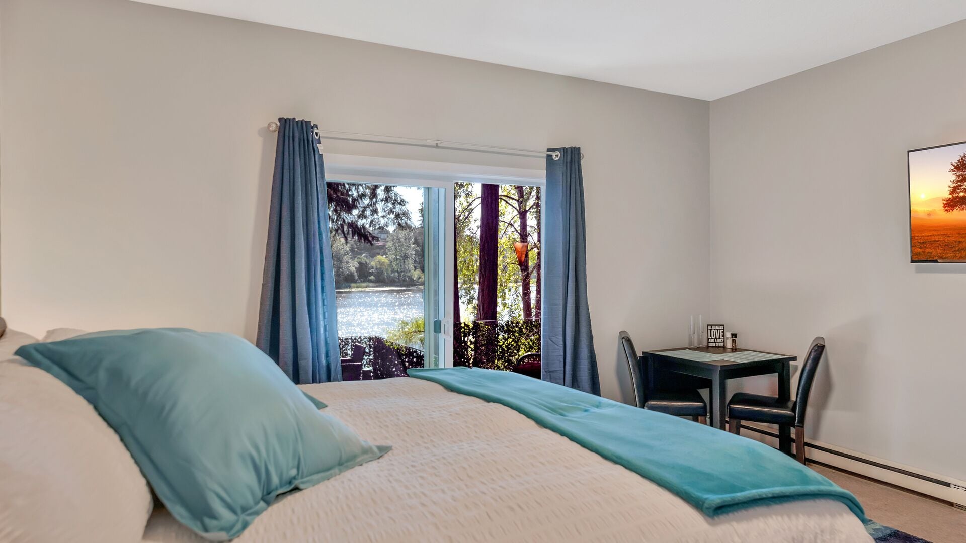 A bedroom with a bed, a desk, and a view of a lake.