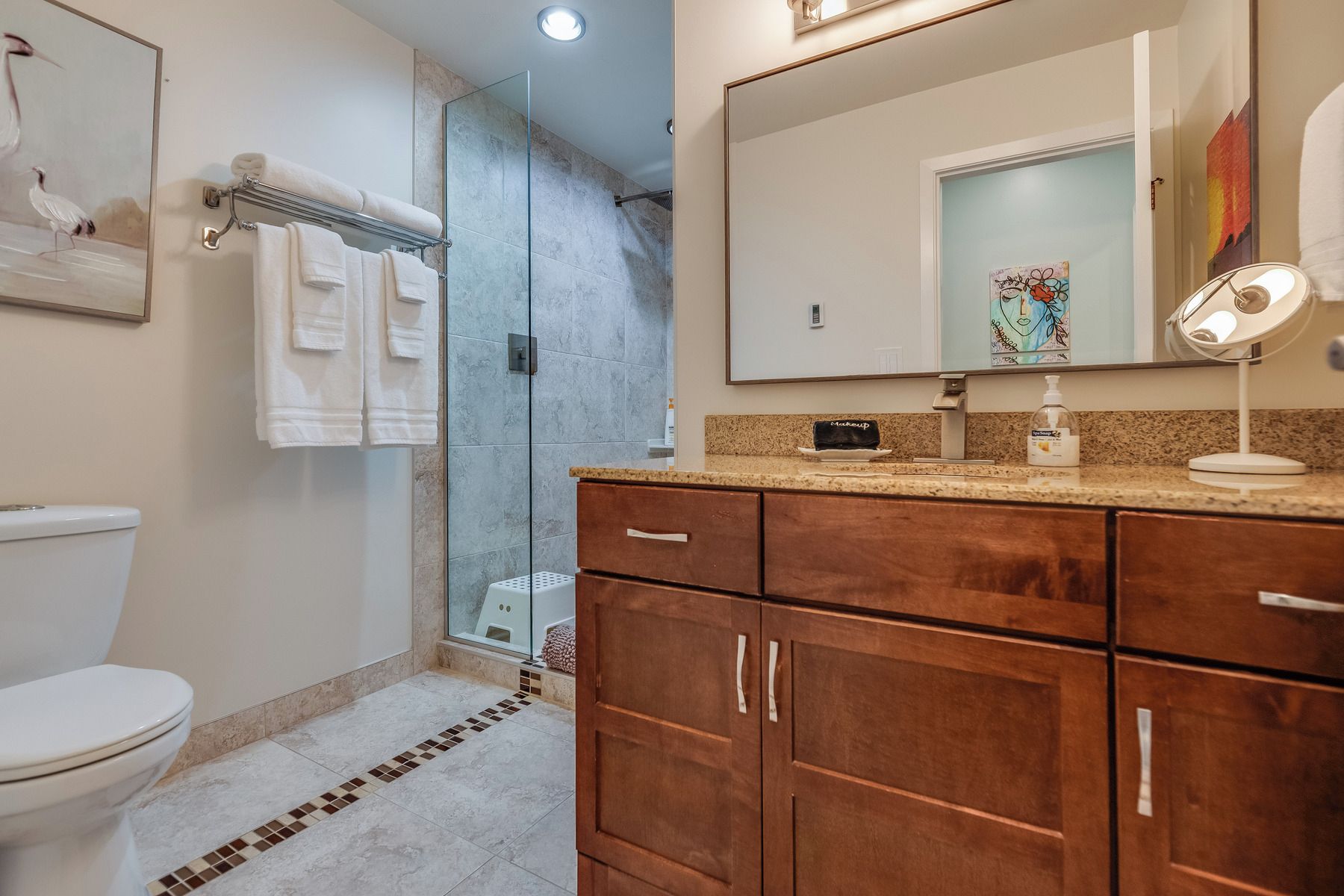 Une salle de bain comprenant des toilettes, une douche, un meuble-lavabo avec un miroir et un évier.