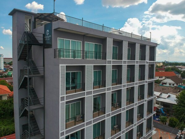 Ein mehrgeschossiges Hotel mit modernem Design, mit Balkonen auf jeder Etage und einer sichtbaren Treppe auf der linken Seite.