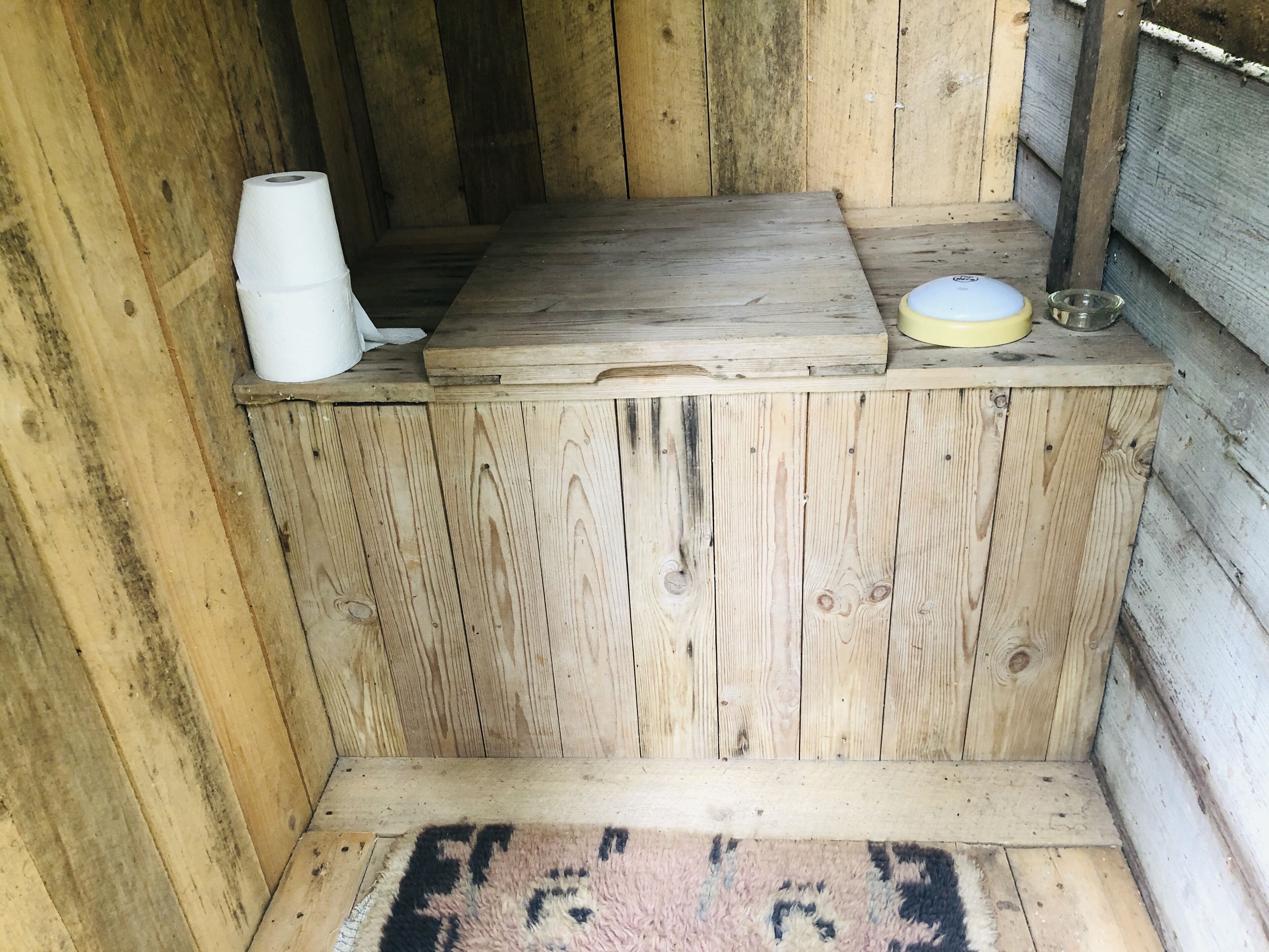 A wooden cabin interior with a bench, a white container, and a yellow object on the bench.