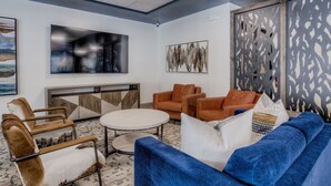 Una sala de estar moderna con un sofá azul, sillones de cuero marrón, una mesa de centro redonda y arte abstracto en las paredes.