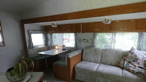 A compact RV interior with a kitchenette, a sofa, and a dining area.