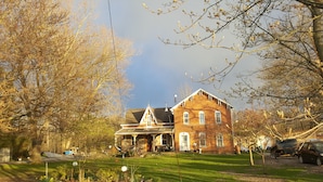 A large brick house with a prominent front porch, surrounded by trees and a well-maintained lawn.