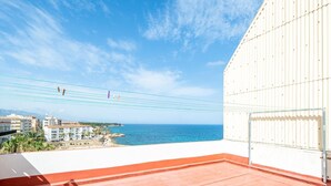 A balcony with a view of the sea, a white building, and a hotel in the background. - Heart of the village sea views only 100m beach (L'Ametlla de Mar)