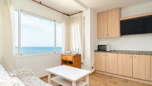 A compact room with a bed, a small table, a microwave, and a view of the sea. - Heart of the village sea views only 100m beach (L'Ametlla de Mar)
