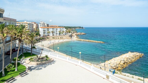 A coastal hotel with a beach, palm trees, and a rocky breakwater. - Heart of the village sea views only 100m beach (L'Ametlla de Mar)
