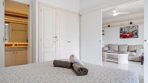 Un dormitorio con cama, baño, sofá y un cuadro.