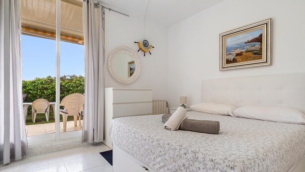 Un dormitorio con cama, un espejo redondo, un cuadro y vistas al exterior.
