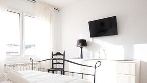 Une chambre à coucher avec un lit, une chaise, un bureau, une télévision et une fenêtre.