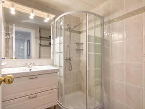 Une salle de bain moderne avec une douche à parois de verre, un meuble-lavabo blanc doté de tiroirs et un grand miroir.