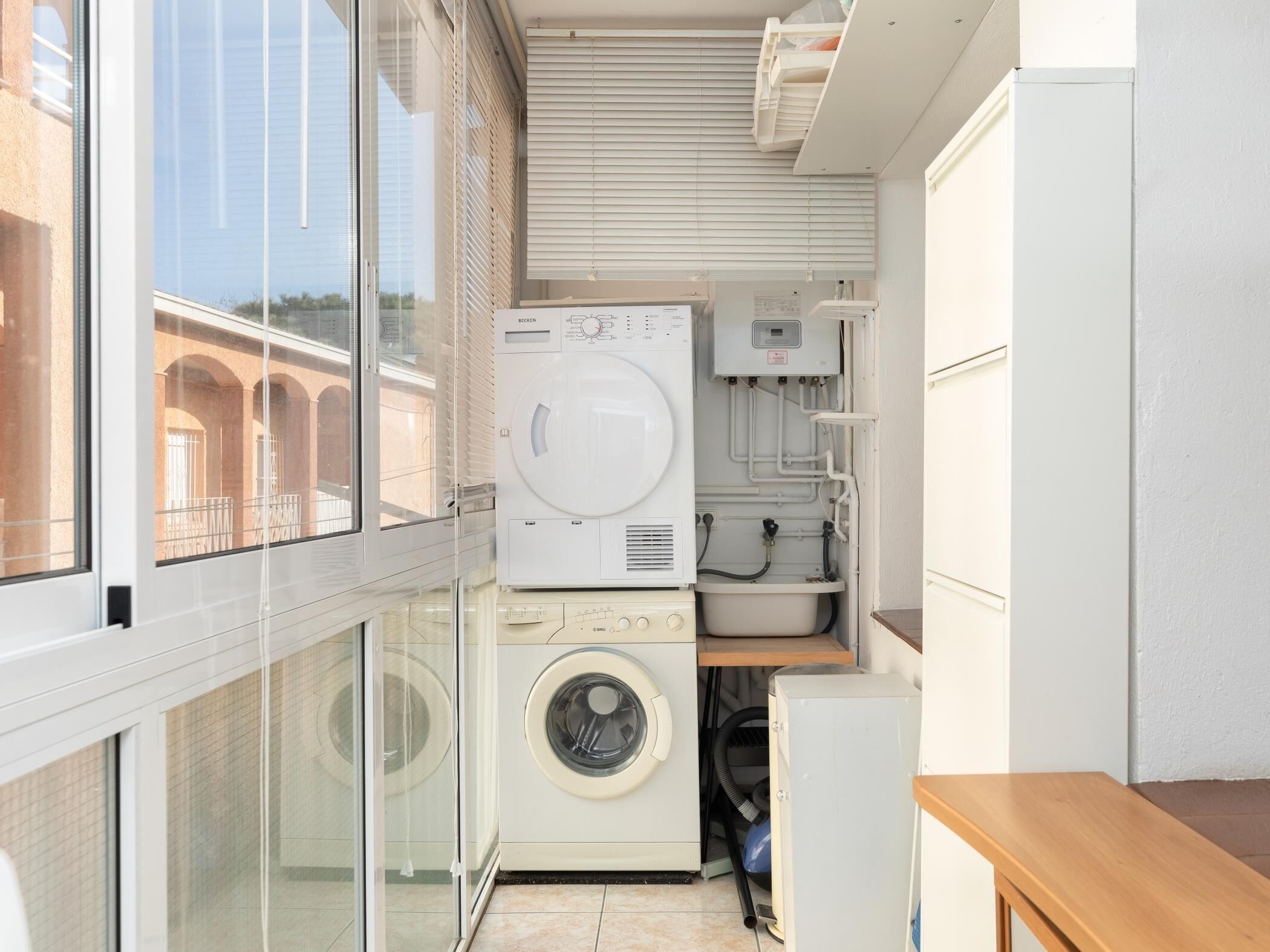 Een kleine wasruimte met een wasmachine, droger en wasbak.