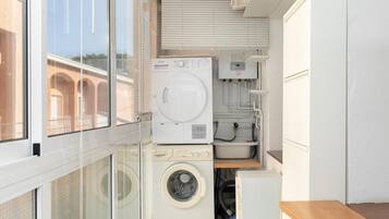 Een kleine wasruimte met een wasmachine, droger en wasbak.