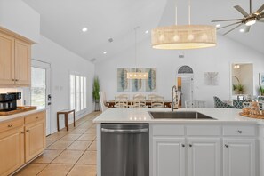 A modern kitchen with a central island, white cabinetry, and a ceiling fan.