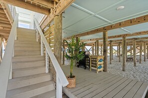A wooden staircase leading to a covered deck area with a grill and seating.