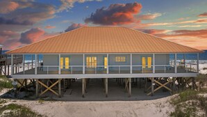 A beachfront house with a wooden deck and multiple windows. - Enjoy a personal beach experience! Expansive gulf side deck! - Dauphin Charm (Dauphin Island)