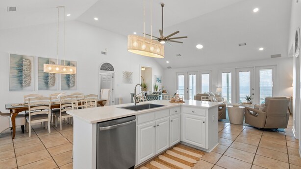 A spacious kitchen with a central island, a dining area with a table and chairs, and a view of the ocean through large windows. - Enjoy a personal beach experience! Expansive gulf side deck! - Dauphin Charm (Dauphin Island)