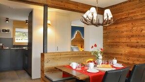 A dining area with a wooden bench, a table set for two, and a chandelier. - Papillon by Interhome (Zermatt)
