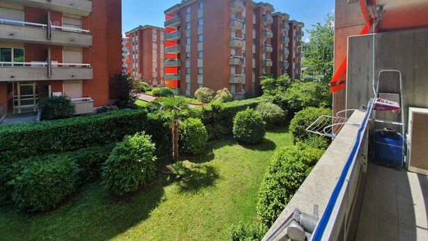 Un immeuble résidentiel doté de nombreux balcons, d’un jardin bien entretenu et offrant une vue sur un ciel dégagé.