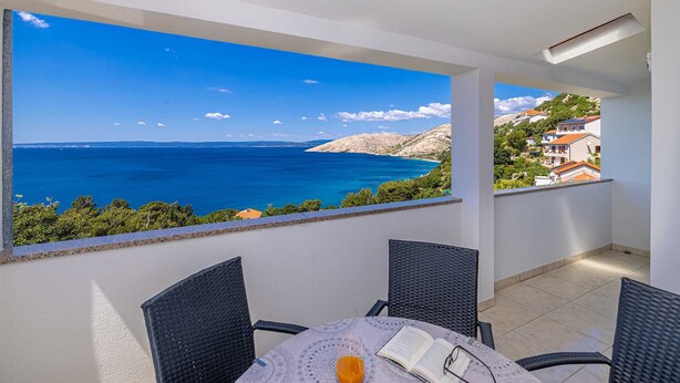 A balcony with a view of the sea and a town. - Apartment STARA BAŠKA with sea view (Stara Baška)