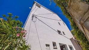 A white building with a sloped roof, multiple windows, and a visible antenna. - Apartment STARA BAŠKA near the sea (Stara Baška)